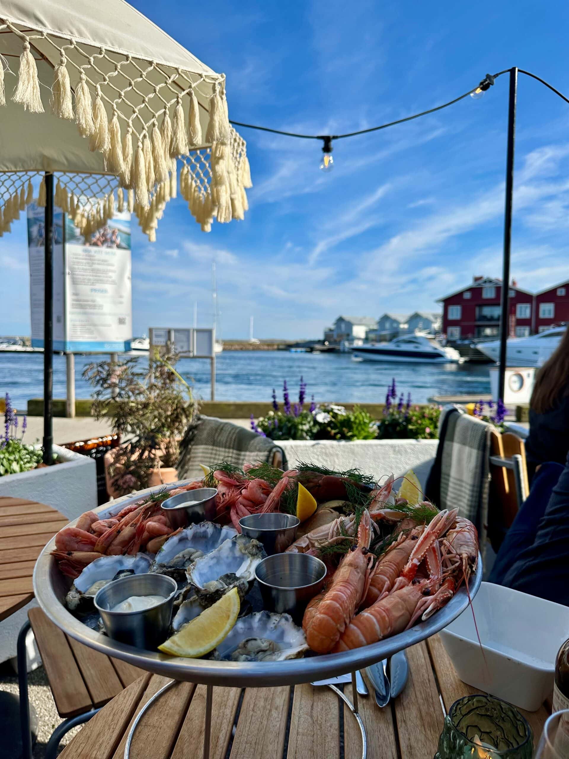 Skärets Krog – Skaldjur på uteservering vid havet Fräscha skaldjur på servering vid havet, med utsikt över båtar och blå himmel.